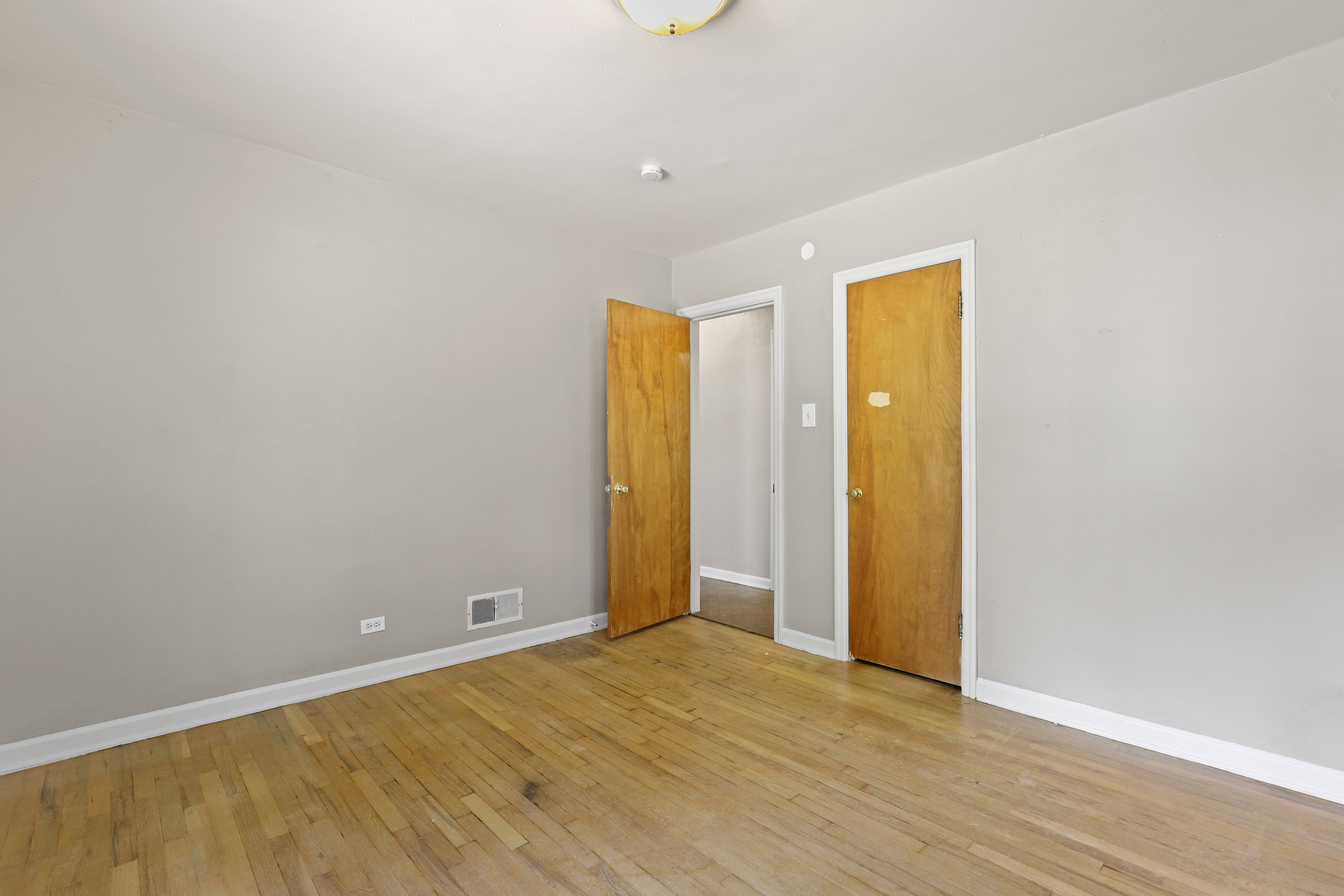 a empty room with a wooden floor and two doors